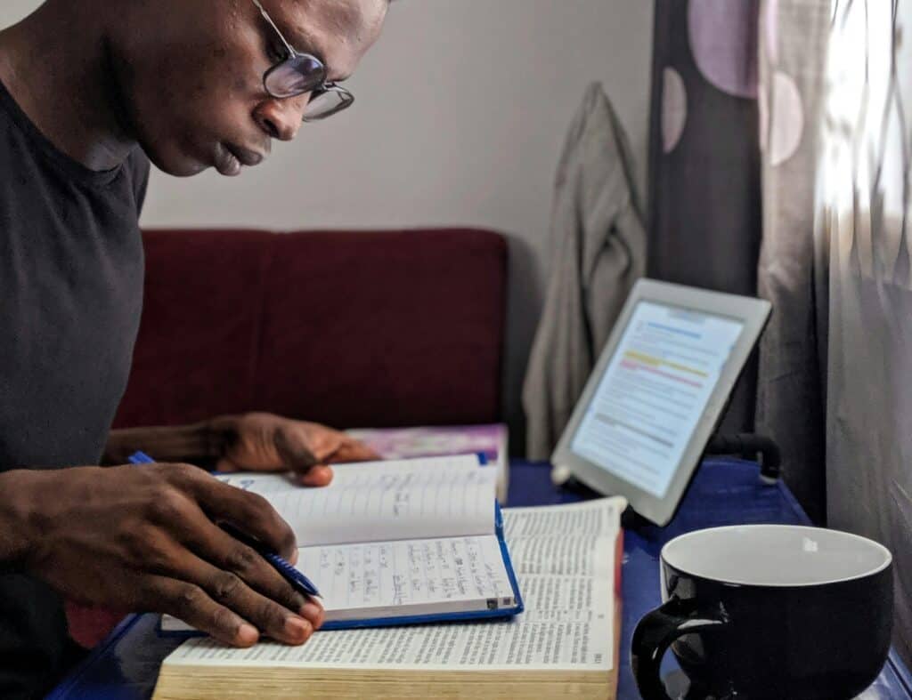 man studying notebook and Bible at desk