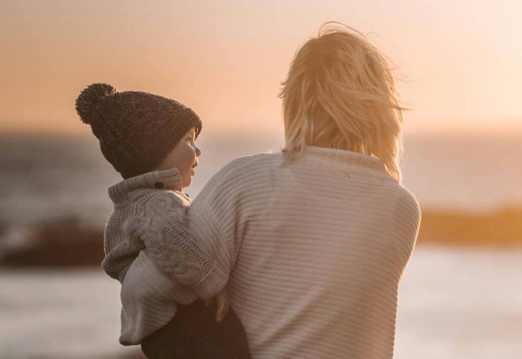 mom holding toddler on beach